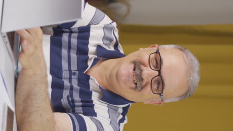 Vertical-video-of-Home-office-worker-old-man-smiling-at-camera.